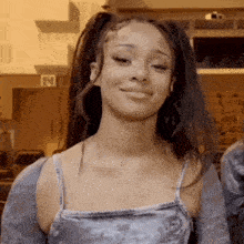 a girl with pigtails is smiling and wearing a gray tank top