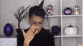 a person wearing a witch hat covering their nose
