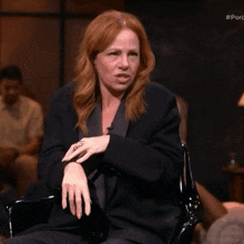 a woman with red hair is sitting in a chair and making a funny face with her hands