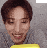 a young man wearing headphones is smiling while looking at a yellow item .