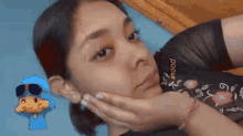 a close up of a woman 's face with her hands on her chin .