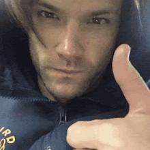 a man in a blue jacket is giving a thumbs up .