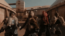 a group of women wearing fur coats are dancing in front of a building with the letter s on it