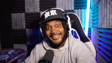 a man wearing headphones and a hat is sitting in a chair in front of a microphone .