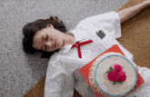 a girl is laying on the floor with a cake on her lap