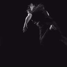 a black and white photo of a person 's arm reaching up in the dark