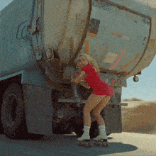 a woman wearing roller skates stands in front of a truck that has a sign on the back that says flammable