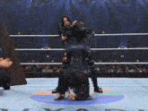 a wrestler holds another wrestler upside down on her back