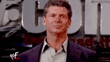 a man in a suit and white shirt is standing in front of a sign that says we