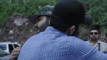a man wearing a hat that says jc on it is hugging another man