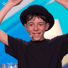 a young boy wearing a black top hat and a microphone with a star on the bottom right