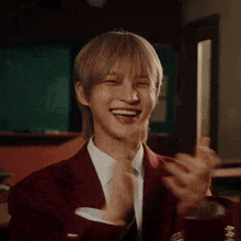 a young man wearing a suit and tie is smiling and giving a thumbs up