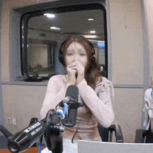 a woman wearing headphones is sitting in front of a microphone that says mitsubishi
