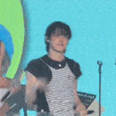 a man wearing a black and white striped shirt is standing in front of a microphone