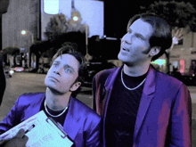 a man in a purple suit is holding a clipboard that says ' a ' on it