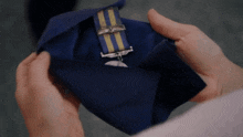 a person is holding a medal in their hands with a blue and yellow ribbon
