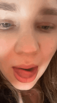 a close up of a girl 's face with her tongue out