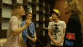 a man wearing a thrasher t-shirt talks to two other men