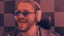 a man wearing headphones and sunglasses laughs with his mouth open