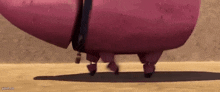 a cartoon pig is walking on a dirt road with a bell around its neck .