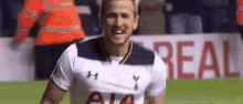 a soccer player is smiling on the field while wearing a white shirt .