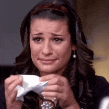 a woman is crying and holding a piece of paper in her hands
