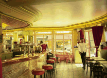 a man in a white shirt stands in a restaurant with a sign on the window that says ' alain '