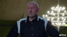 a man in a black and white shirt is standing in front of a netflix sign