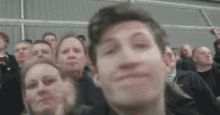a man is making a funny face in front of a crowd .