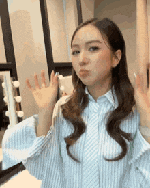 a woman wearing a striped shirt is waving her hand