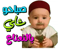 a baby with a mustache is holding a glass of tea with arabic writing behind him