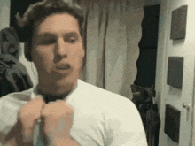 a man in a white shirt is adjusting his tie in front of a door