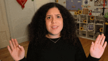 a woman with curly hair making a funny face in front of a shelf that says twitch on it