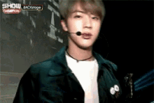 a young man is standing in front of a microphone and looking at the camera .