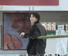 a man in a black jacket stands in front of a sign that says ' extra '