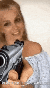 a woman is smiling while holding a gun in her hand .