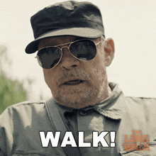 a man wearing sunglasses and a hat says " walk " in white letters
