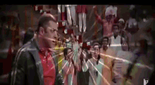 a man in a red shirt is standing in front of a crowd