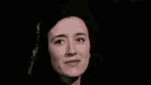 a close up of a woman 's face in a dark room making a funny face .