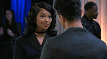 a man in a black suit stands in front of a woman in a black dress