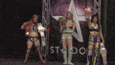 three female wrestlers standing in front of a sign that says ' stardom '