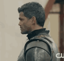 a man in armor is standing in a room and looking to the side .