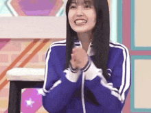 a young woman in a blue jacket is clapping her hands .