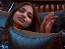 a woman is laying on a couch with a blue pillow and making a face .