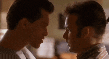 two men are looking at each other with their eyes closed in a room .
