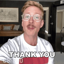 a man wearing glasses and a white shirt with the words thank you on it
