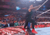 a wrestler is jumping over a rope in a wrestling ring while wearing red shoes .
