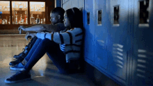 a man and a woman sit on the floor next to lockers