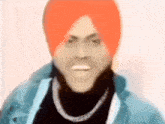 a man wearing a turban and a blue jacket is making a funny face