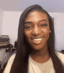 a woman with long hair is smiling and looking at the camera in a room .